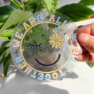 Macro shot of circular suncatcher sticker with rainbow effect and smiling flower face