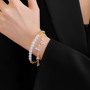 Dettaglio di un bracciale dorato a più strati con perle finte sul polso di una modella
