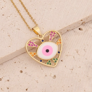 Detail of gold heart necklace with evil eye zircon pendant on beige stone background