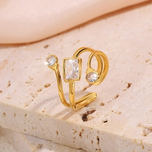 Detail of gold titanium steel open ring featuring a rectangular and two round crystals