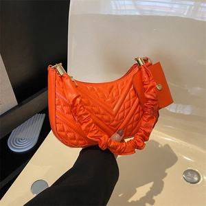 Detail of orange quilted tote bag with scrunchie handle and matching mini pouch bag