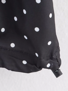Détail du tissu noir à pois avec cordon de serrage réglable à l'ourlet et couture de qualité