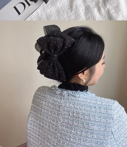 Detail view of large black tulle bow hair claw clip with delicate white polka dots