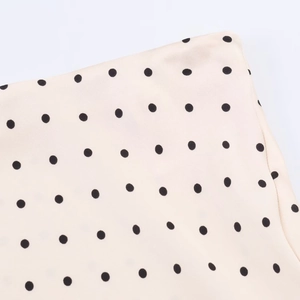 Detailed macro view of smooth cream fabric featuring classic black polka dot patterns
