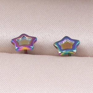Macro shot of rainbow plated star earrings on pink satin showing metallic texture