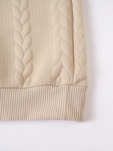 Macro shot of warm beige knitted sweater featuring ribbed hem and premium 3D textured pattern