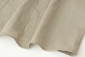 Detail shot of breathable light khaki faux linen fabric with clean hemline stitching