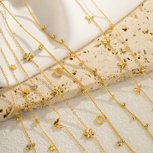 Detail of layered gold chains with heart, star, and flower charms on textured stone
