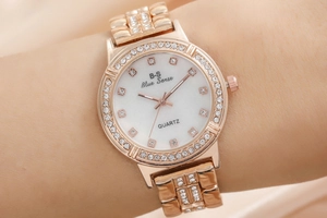 Close-up of rose gold quartz watch with rhinestone-encrusted bezel and white pearly dial