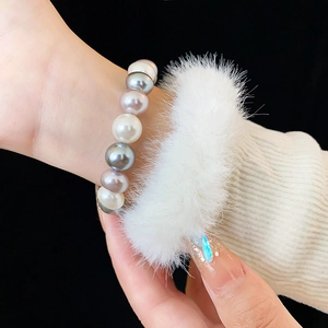 Detail of multi-color pearl bracelet featuring white, gray and purple pearls on wrist