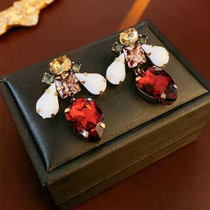 Detail of vintage bee-shaped earrings with colorful crystals on a black leather box