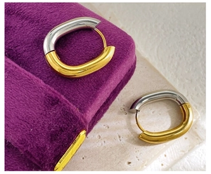 Macro detail of two-tone U-shaped earrings on velvet jewelry box and stone slab