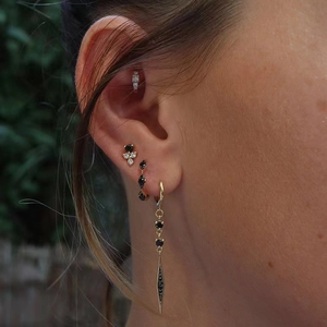 Macro view of gold S925 silver ear cuff and long sword pendant earring with black gemstones