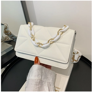 Detail of white quilted crossbody bag featuring a golden chain and printed wide shoulder strap