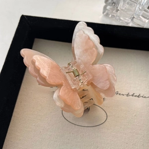 Detail of a butterfly hair claw clip with pink marble finish and gold glitter accents