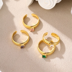 Detail of four gold-plated open rings featuring colorful square-cut zircon gemstones