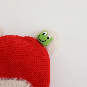 Close-up of baby winter knit hat with red yarn texture and plush white faux fur lining