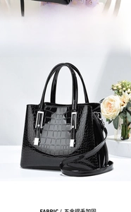 Détail du sac à main noir brillant à motif crocodile avec poignées renforcées en argent