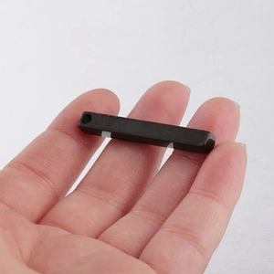 Polished black rectangular pendant in stainless steel held on finger for scale