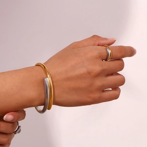 Detail of two-tone gold and silver overlapping ring and bracelet set on a model