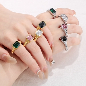 Detail of croissant texture rings with emerald and pink rectangle gemstones on fingers