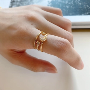 Detail of layered gold star and moon rings with sparkling zircon accents on finger
