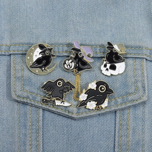 Detailansicht der Emaille-Anstecknadeln mit Rabenmotiv an einer hellblauen Jeansjacke