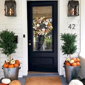Symmetric porch display featuring white pumpkins and autumn wreaths in metal buckets