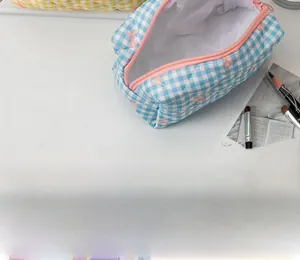 Quilted blue gingham cosmetic bag with pink bow pattern and pink zipper detail