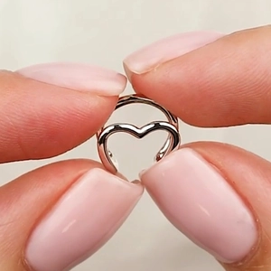 Macro shot of double-layered hollow heart ring in silver finish held by fingers