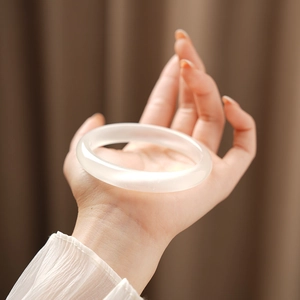 Close-up of a smooth white cat-eye stone bangle with polished finish and oily luster
