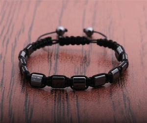 Close-up of hand-woven black cord bracelet with metallic hematite square beads