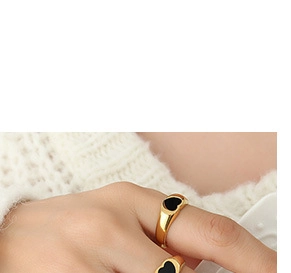 Close-up of gold band ring with black heart enamel worn by a model in lifestyle shot