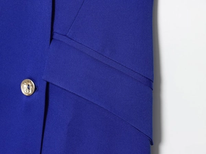 Détail de la robe blazer bleu roi montrant le tissu texturé et le bouton doré gaufré