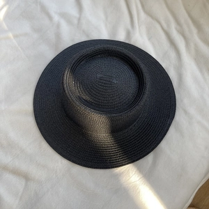 Detailed top-down view of black woven straw hat showing fine spiral texture and craftsmanship