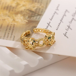 Macro detail of gold open ring featuring twin leopard heads with green crystal eyes