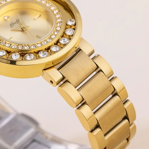 Macro shot of gold women's watch featuring a diamond-set dial and metal link bracelet