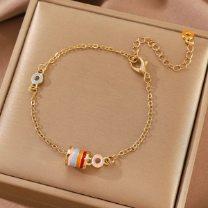 Detailed close-up of golden necklace with colorful enamel beads and charms on velvet
