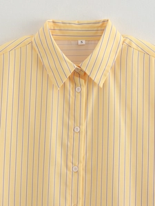Detail of yellow striped cotton shirt showing collar, white buttons and fabric texture