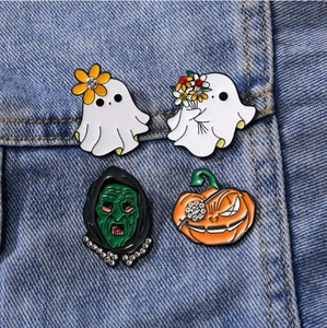 Close-up of four spooky Christmas enamel pins with rhinestones on blue denim jacket