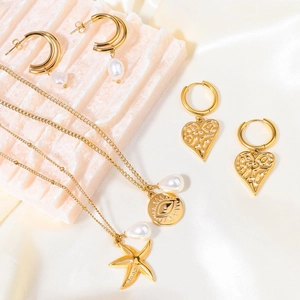 Detail of 18K gold-plated star pendants and pearl earrings on pink stone decor