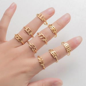 Close-up of gold stainless steel angel number rings 111-999 on a female model's fingers