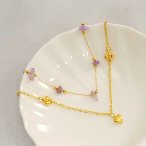 Detail of gold heart pendant and purple natural stone on stainless steel bracelet