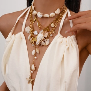 Detail of layered gold choker with shell and starfish charms on model's neck