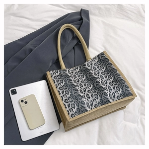 Detail of leopard print suede tote bag with natural linen trim and square handle design