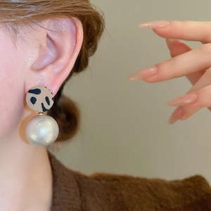Gros plan de boucles d'oreilles léopard vintage avec grandes perles blanches sur un mannequin