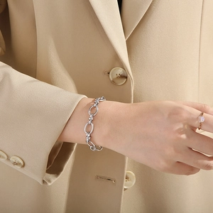 Silver stainless steel paperclip link bracelet worn by a model in a professional outfit