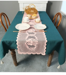 Close-up of pink hollow lace table runner over dark green fabric for home decoration