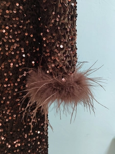 Vue détaillée des paillettes marron foncé et des poignets en plumes d'autruche de la robe