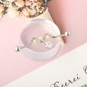 Macro view of industrial barbell earring with S-wave design and star zircon pendant